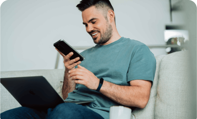 Hombre sonriente usando smartphone y laptop